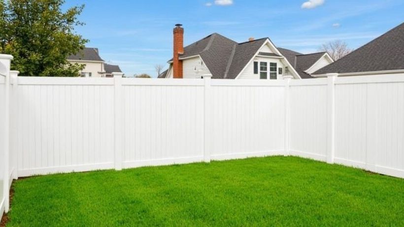 White vinyl privacy fence wrapping the corner of a grassy backyard